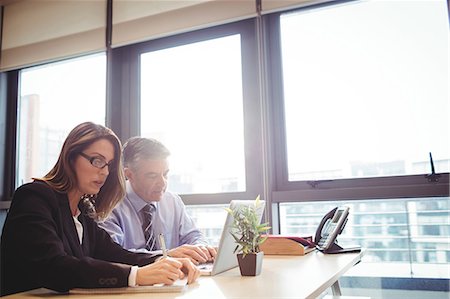 simsearch:6109-08700458,k - Businessman discussing with colleague over laptop in office Stock Photo - Premium Royalty-Free, Code: 6109-08701303