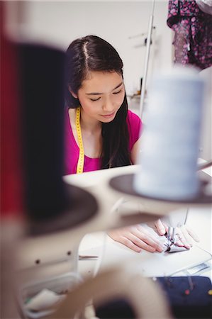 simsearch:6109-08701535,k - Female dressmaker sewing on the sewing machine in the studio Stock Photo - Premium Royalty-Free, Code: 6109-08701549