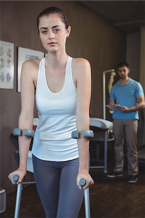 Portrait of female patient walking with crutch in the clinic Stock Photo - Premium Royalty-Free, Code: 6109-08701771