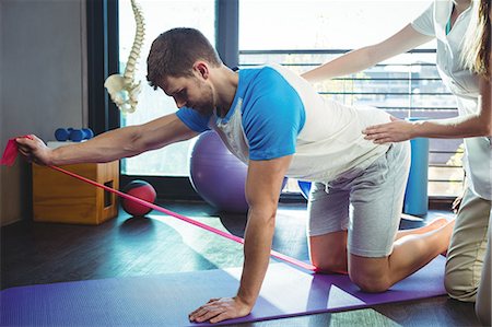 Female physiotherapist assisting a male patient while exercising in the clinic Foto de stock - Sin royalties Premium, Código: 6109-08701722