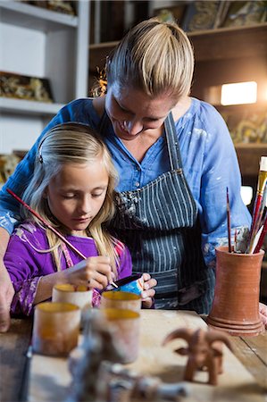 Female potter assisting girl in painting at pottery workshop Stock Photo - Premium Royalty-Free, Code: 6109-08705508
