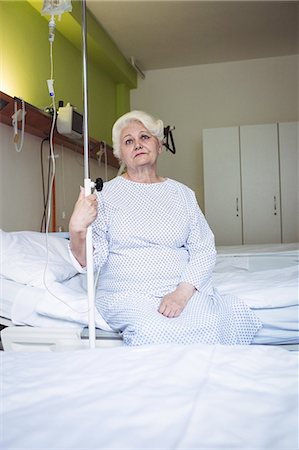 Thoughtful senior woman sitting on bed in hospital Stock Photo - Premium Royalty-Free, Code: 6109-08720311