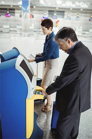 Business people using self service check-in machine at airport Stock Photo - Premium Royalty-Free, Code: 6109-08722512