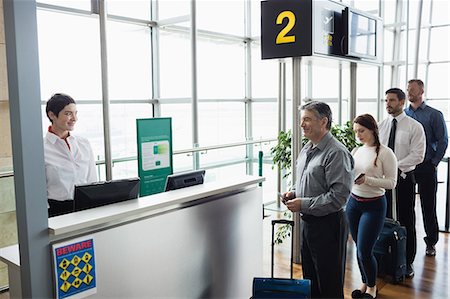Passengers waiting in queue at check-in counter in airport terminal Foto de stock - Sin royalties Premium, Código: 6109-08722654