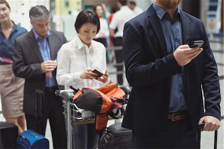 people waiting in line - Passengers waiting in queue at a check-in counter with luggage inside the airport terminal Stock Photo - Premium Royalty-Free, Code: 6109-08722751