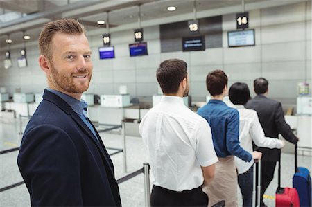 suitcase airport departure - Passengers waiting in queue at a check-in counter with luggage inside the airport terminal Stock Photo - Premium Royalty-Free, Code: 6109-08722767