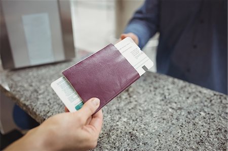 simsearch:400-03938985,k - Airline check-in attendant handing passport to passenger at airport check-in counter Foto de stock - Sin royalties Premium, Código: 6109-08722716