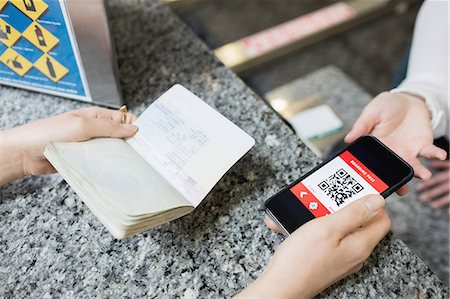 Passenger giving a passport and mobile phone to an airline check-in attendant at check-in counter Stock Photo - Premium Royalty-Free, Code: 6109-08722730