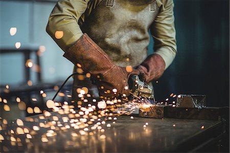 Mid-section of male welder working on a piece of metal in workshop Stock Photo - Premium Royalty-Free, Code: 6109-08722835