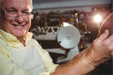 Portrait of shoemaker holding a shoe in workshop Stock Photo - Premium Royalty-Free, Code: 6109-08722933