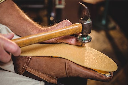 Shoemaker hammering on a shoe in workshop Stock Photo - Premium Royalty-Free, Code: 6109-08722931