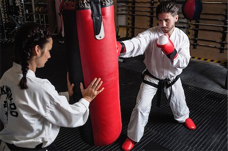 Man and woman practicing karate with punching bag in studio Stock Photo - Premium Royalty-Free, Code: 6109-08739197