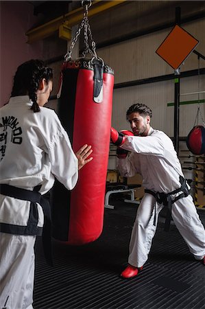 simsearch:400-04347301,k - Man and woman practicing karate with punching bag in studio Photographie de stock - Premium Libres de Droits, Code: 6109-08739196