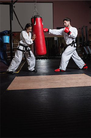 Man and woman practicing karate with punching bag in studio Stock Photo - Premium Royalty-Free, Code: 6109-08739199