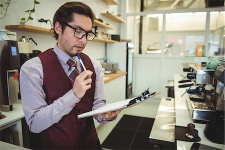 restaurant counter - Thoughtful man looking at clipboard in coffee shop Stock Photo - Premium Royalty-Free, Code: 6109-08802039