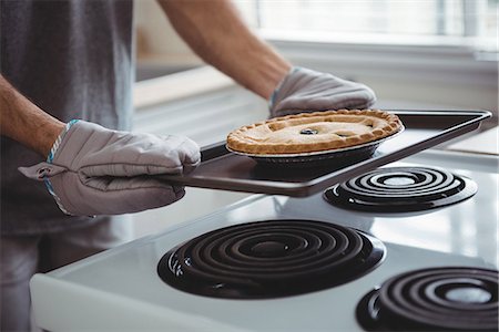 Mid section of man holding a tray of freshly baked tart in the kitchen at home Stock Photo - Premium Royalty-Free, Code: 6109-08802269