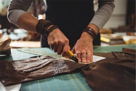 Mid-section of craftswoman cutting leather in workshop Stock Photo - Premium Royalty-Free, Code: 6109-08802357