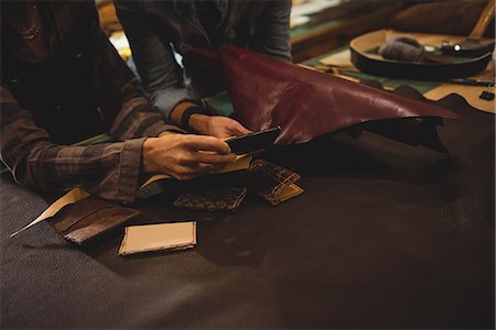 simsearch:693-06379747,k - Craftswomen discussing over a sheet of leather in workshop Stock Photo - Premium Royalty-Free, Code: 6109-08802369