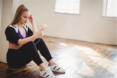 simsearch:6109-08802676,k - Pretty woman listening to music on mobile phone in hip hop dance studio Stock Photo - Premium Royalty-Free, Code: 6109-08802664
