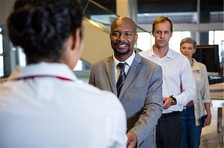 professional (pertains to traditional blue collar careers) - Businessman handing over his boarding pass to the female staff at airport terminal Stock Photo - Premium Royalty-Free, Code: 6109-08802792