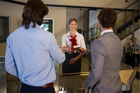 simsearch:400-03938985,k - Female staff checking boarding pass of passengers at check-in counter in airport Foto de stock - Sin royalties Premium, Código: 6109-08802861