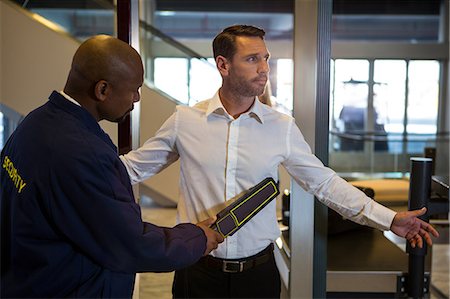 Security guard frisking a passenger at airport terminal Stock Photo - Premium Royalty-Free, Code: 6109-08802803