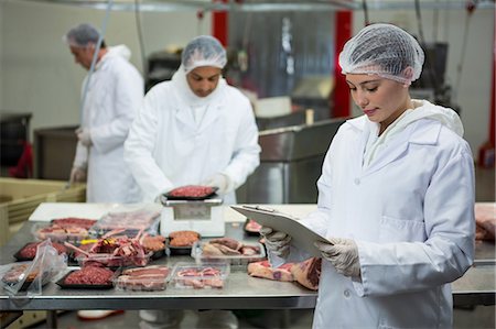 Female butcher maintaining records on clipboard at meat factory Stock Photo - Premium Royalty-Free, Code: 6109-08802933