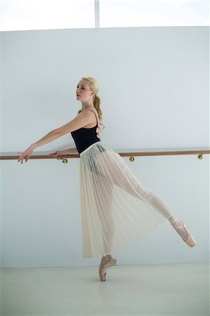 simsearch:400-07725556,k - Ballerina stretching on a barre while practicing ballet dance in the studio Stock Photo - Premium Royalty-Free, Code: 6109-08803033