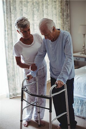 Mid section of senior woman helping senior man to walk with walker at home Stock Photo - Premium Royalty-Free, Code: 6109-08803109