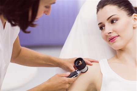 simsearch:6109-08804015,k - Dermatologist examining skin of patient with dermatoscope in clinic Stock Photo - Premium Royalty-Free, Code: 6109-08803987