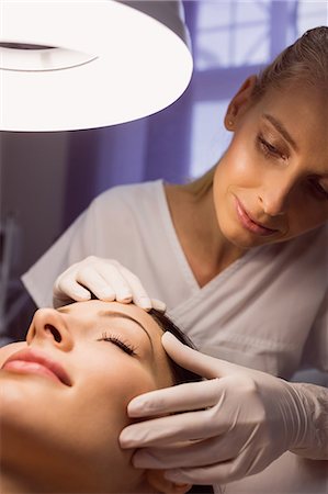 simsearch:6109-08804015,k - Dermatologist examining female patient skin in clinic Stock Photo - Premium Royalty-Free, Code: 6109-08804028