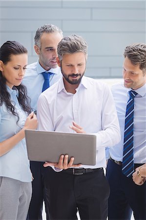 sophisticate - Group of businesspeople discussing over laptop outside office building Stock Photo - Premium Royalty-Free, Code: 6109-08804232