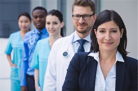 simsearch:6109-08804356,k - Portrait of smiling doctors standing in row at hospital premises Stock Photo - Premium Royalty-Free, Code: 6109-08804343