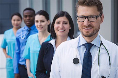 simsearch:6109-08804356,k - Portrait of smiling doctors standing in row at hospital premises Stock Photo - Premium Royalty-Free, Code: 6109-08804342