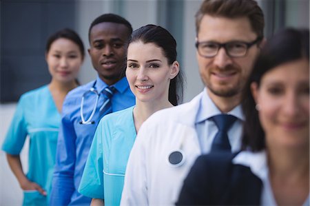 simsearch:6109-08804356,k - Portrait of smiling doctors standing in row at hospital premises Stock Photo - Premium Royalty-Free, Code: 6109-08804344