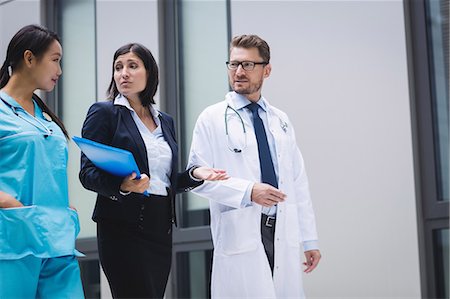 simsearch:6109-08804356,k - Doctors and nurse interacting while walking in hospital premises Stock Photo - Premium Royalty-Free, Code: 6109-08804329