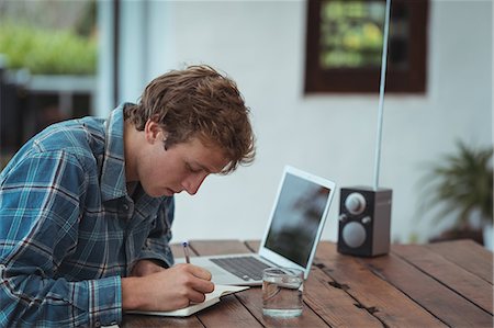 simsearch:6109-08395080,k - Man sitting at table and writing notes on at home Stock Photo - Premium Royalty-Free, Code: 6109-08804585