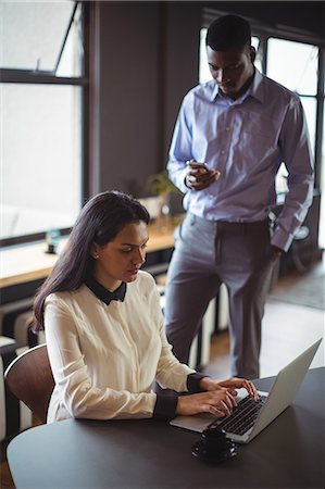 simsearch:6109-08700458,k - Businesswoman working on laptop while man using mobile phone in office Stock Photo - Premium Royalty-Free, Code: 6109-08805068