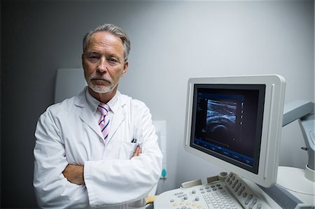 Surgeon with arms crossed standing near ultrasonic device machine Stock Photo - Premium Royalty-Free, Code: 6109-08830011