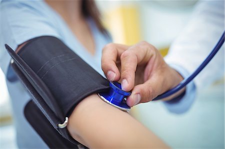 Doctor checking female patient blood pressure Stock Photo - Premium Royalty-Free, Code: 6109-08830171