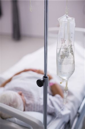 Close-up of iv drip bottle next to the patients bed Stock Photo - Premium Royalty-Free, Code: 6109-08830431