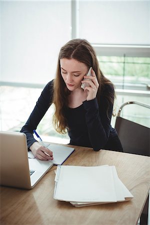 simsearch:6109-08395080,k - Business executive writing on diary while talking on mobile phone Stock Photo - Premium Royalty-Free, Code: 6109-08830658