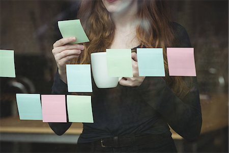 simsearch:6109-08700445,k - Business executive looking at sticky note while having cup of coffee Stock Photo - Premium Royalty-Free, Code: 6109-08830794