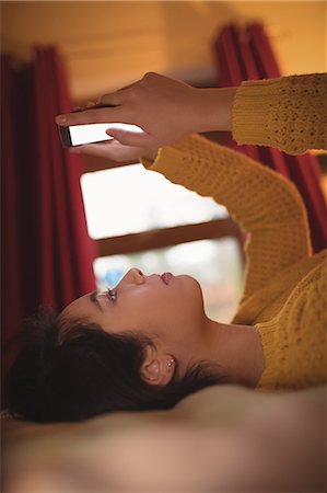 simsearch:845-05838374,k - Woman lying and using mobile phone on bed in bedroom at home Stock Photo - Premium Royalty-Free, Code: 6109-08944395