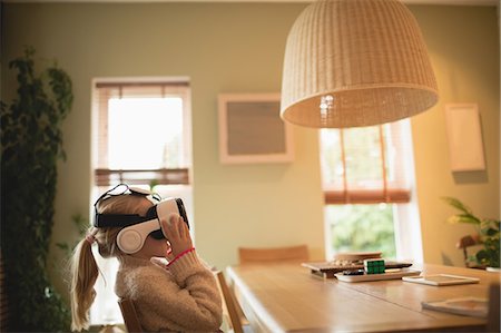 Girl sitting at table and using virtual realty headset at home Stock Photo - Premium Royalty-Free, Code: 6109-08944533