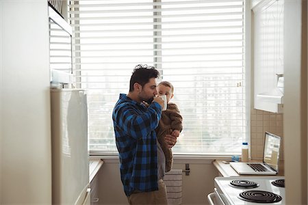 simsearch:6116-07236010,k - Father having coffee while holding his baby in kitchen Stock Photo - Premium Royalty-Free, Code: 6109-08944665