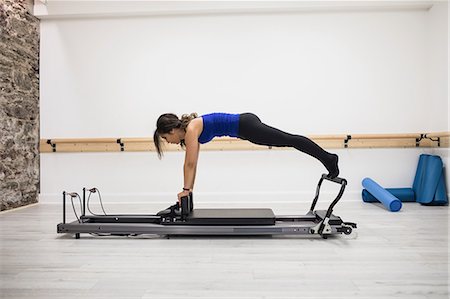 simsearch:6108-06906954,k - Woman exercising on reformer in gym Stock Photo - Premium Royalty-Free, Code: 6109-08944785