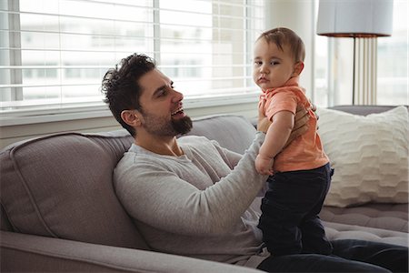 simsearch:700-06758135,k - Father playing with his baby on sofa in living room at home Stock Photo - Premium Royalty-Free, Code: 6109-08944700