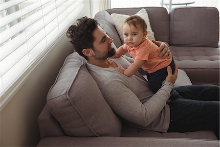 simsearch:700-06758135,k - Father playing with his baby on sofa in living room at home Stock Photo - Premium Royalty-Free, Code: 6109-08944702