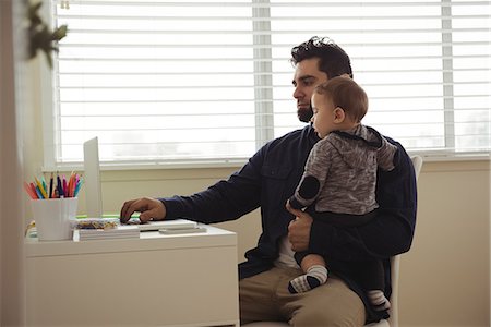 simsearch:6116-07236010,k - Father holding his baby while using laptop at desk at home Stock Photo - Premium Royalty-Free, Code: 6109-08944707